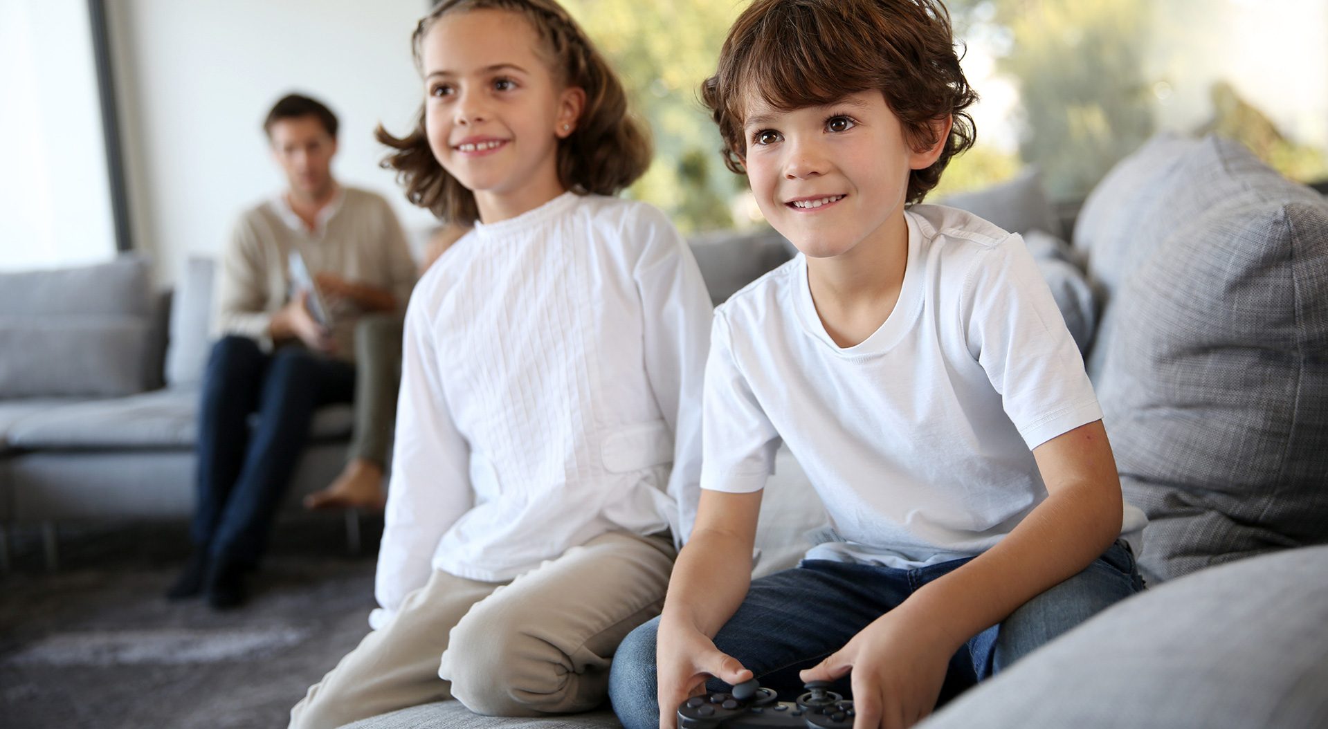 Two kids sitting on sofa with playing video games
