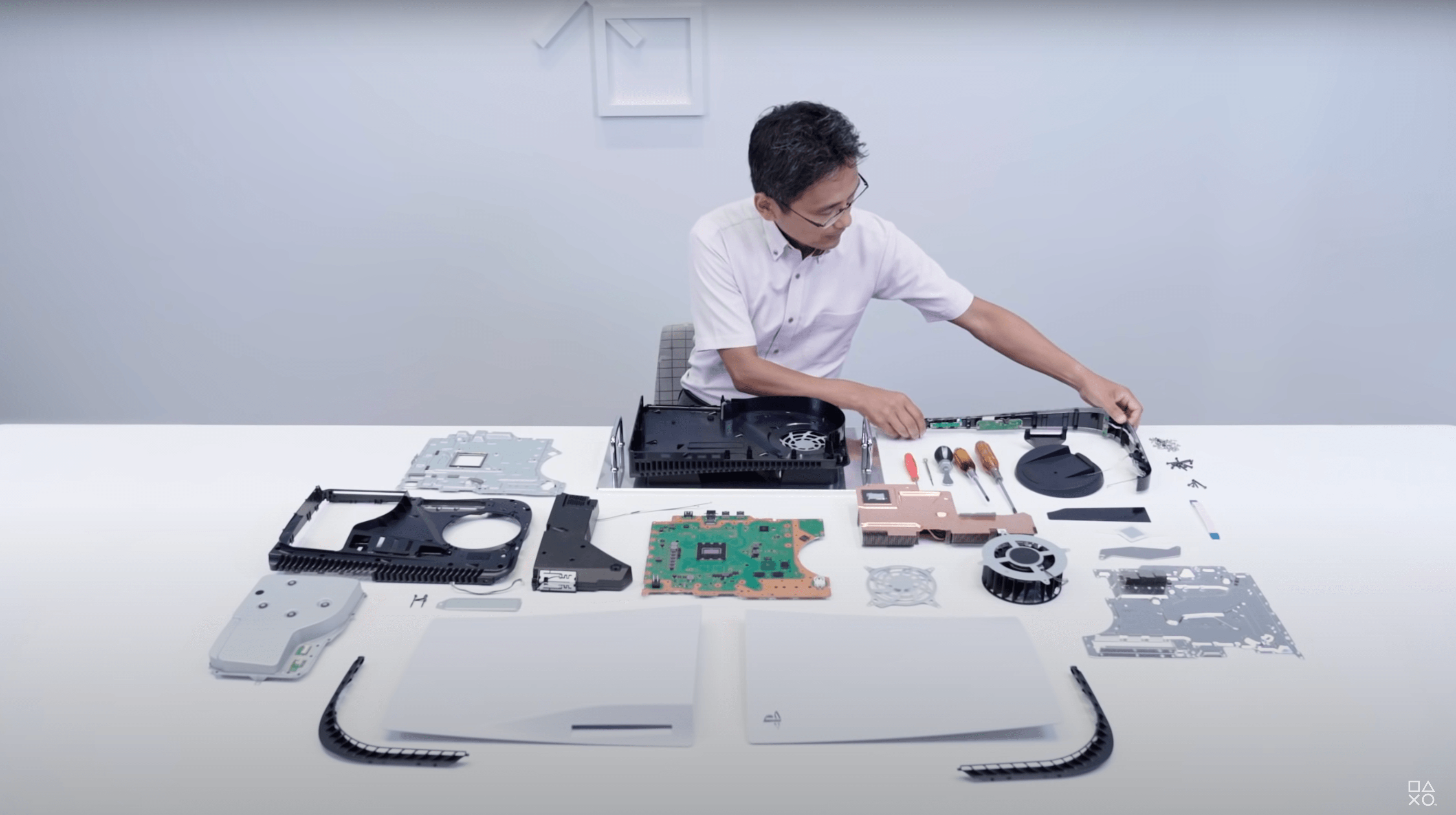 A man is putting together some sort of product - he appears to be doing an engineering review of hardware alone in a conference room