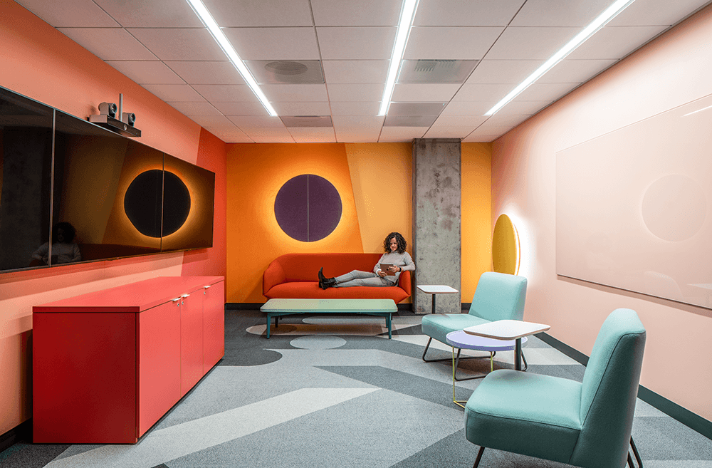 Empty employee breakroom that's decorated in mid century modern design and very bright colors such as red and orange walls and green furniture.