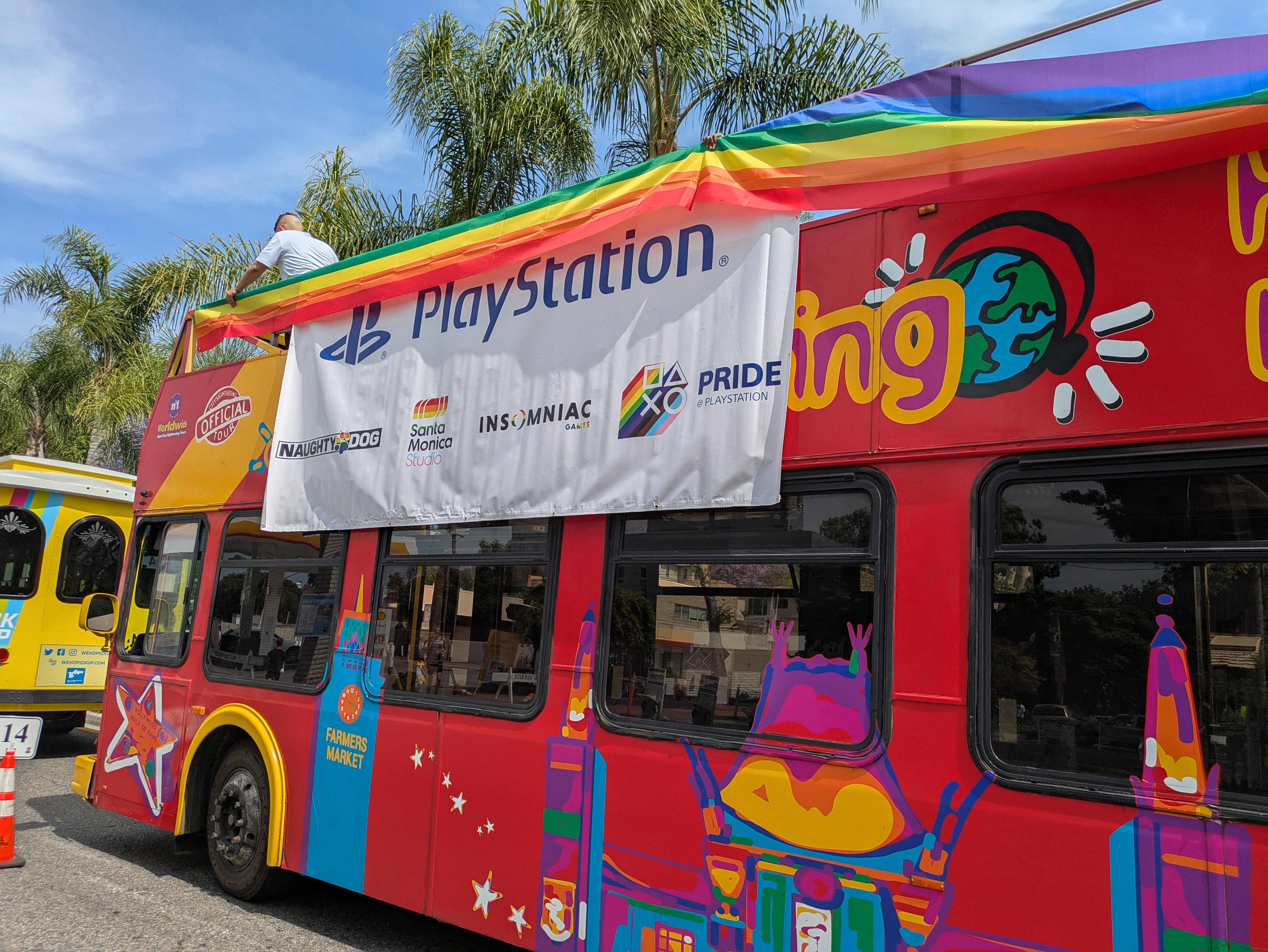 A double-decker bus decorated with a PlayStation logo banner.
