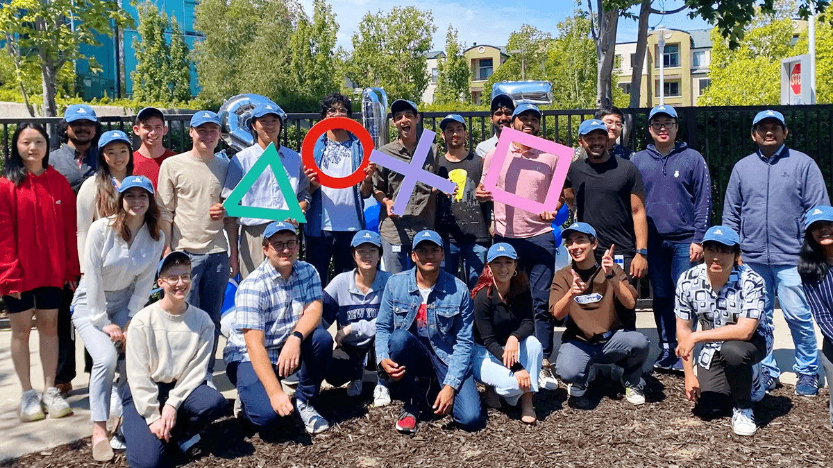 A group of Sony Interactive Entertainment interns all wearing matching blue hats posing for a photo outdoors.