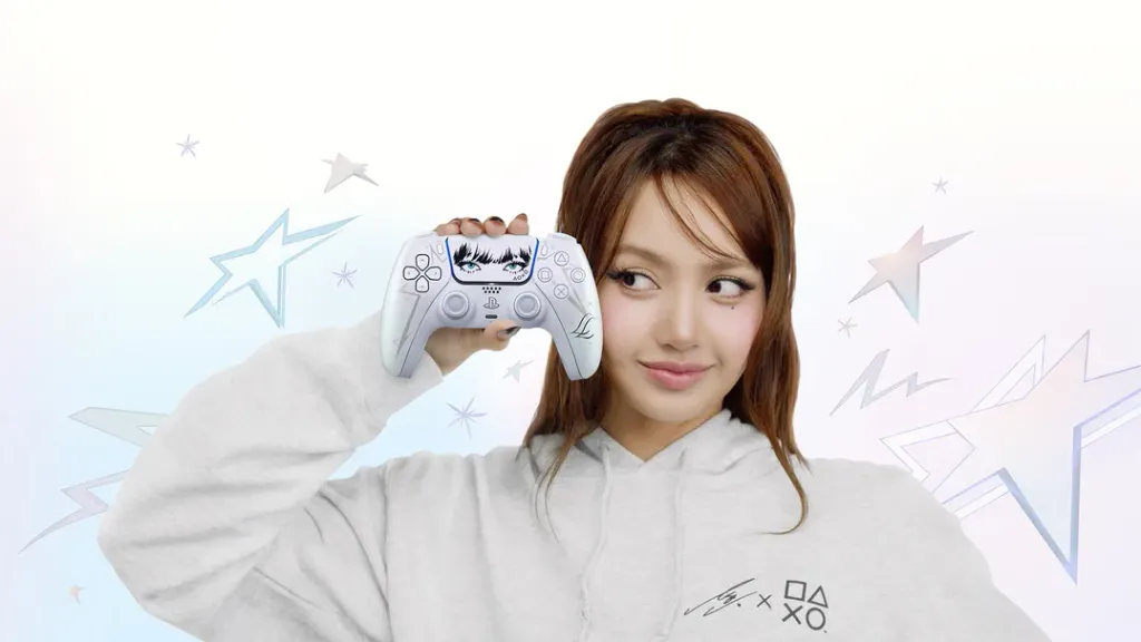 LISA wears a white PlayStation hoodie and holds a customized DualSense wireless controller featuring illustrated eyes beside her face, against a white background decorated with pastel-colored stars and geometric shapes.