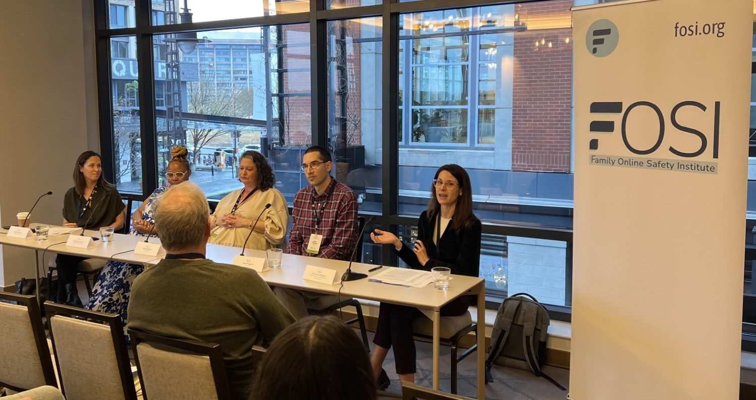 A group of people sitting at a desk at the FOSI panel in a office space.