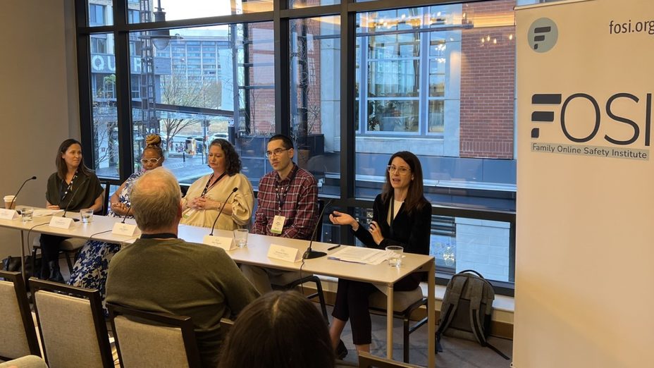 A group of people sitting at a desk at the FOSI panel in a office space.