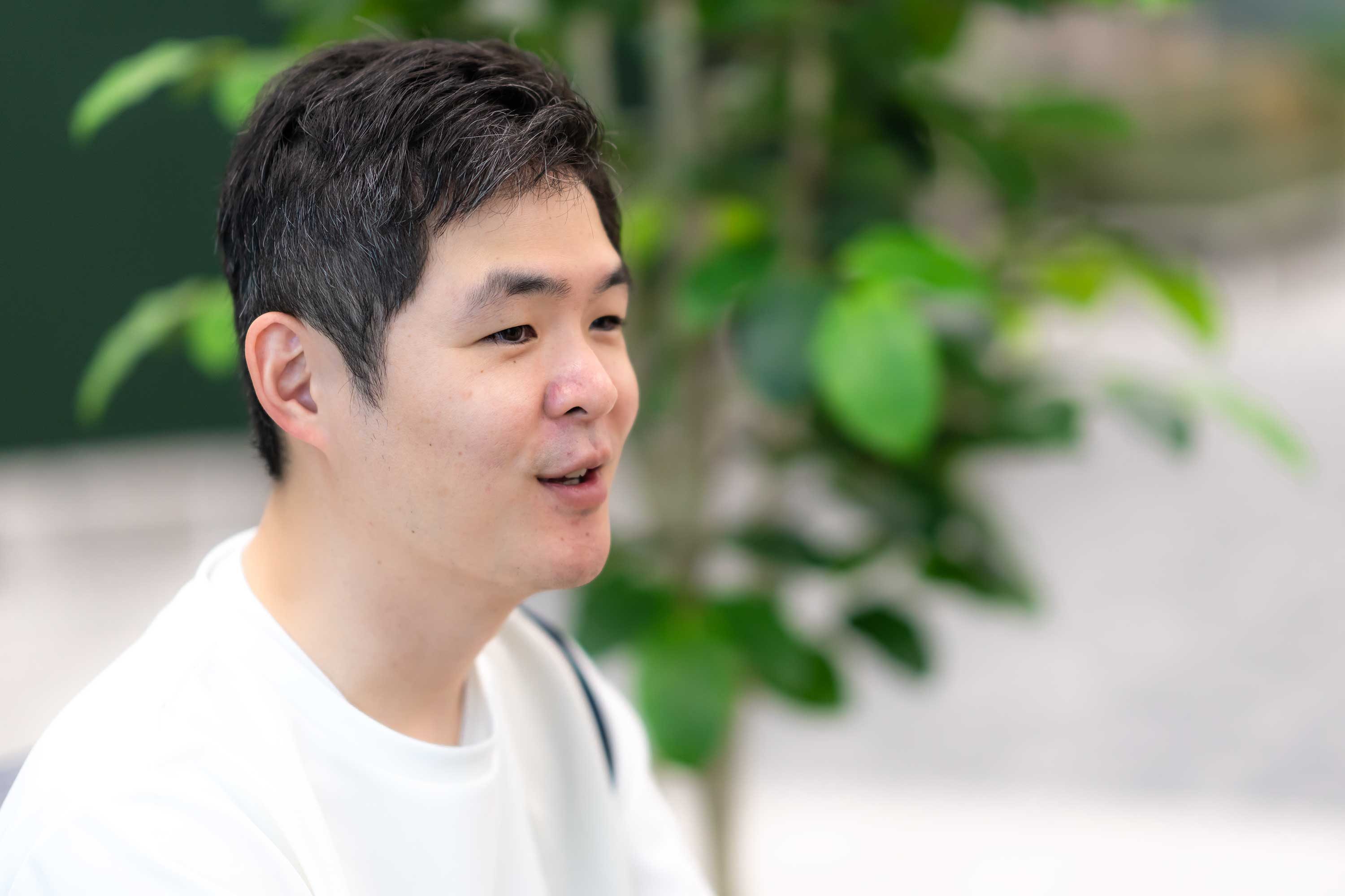 緑の植物を背景に、白い服の社員が話している