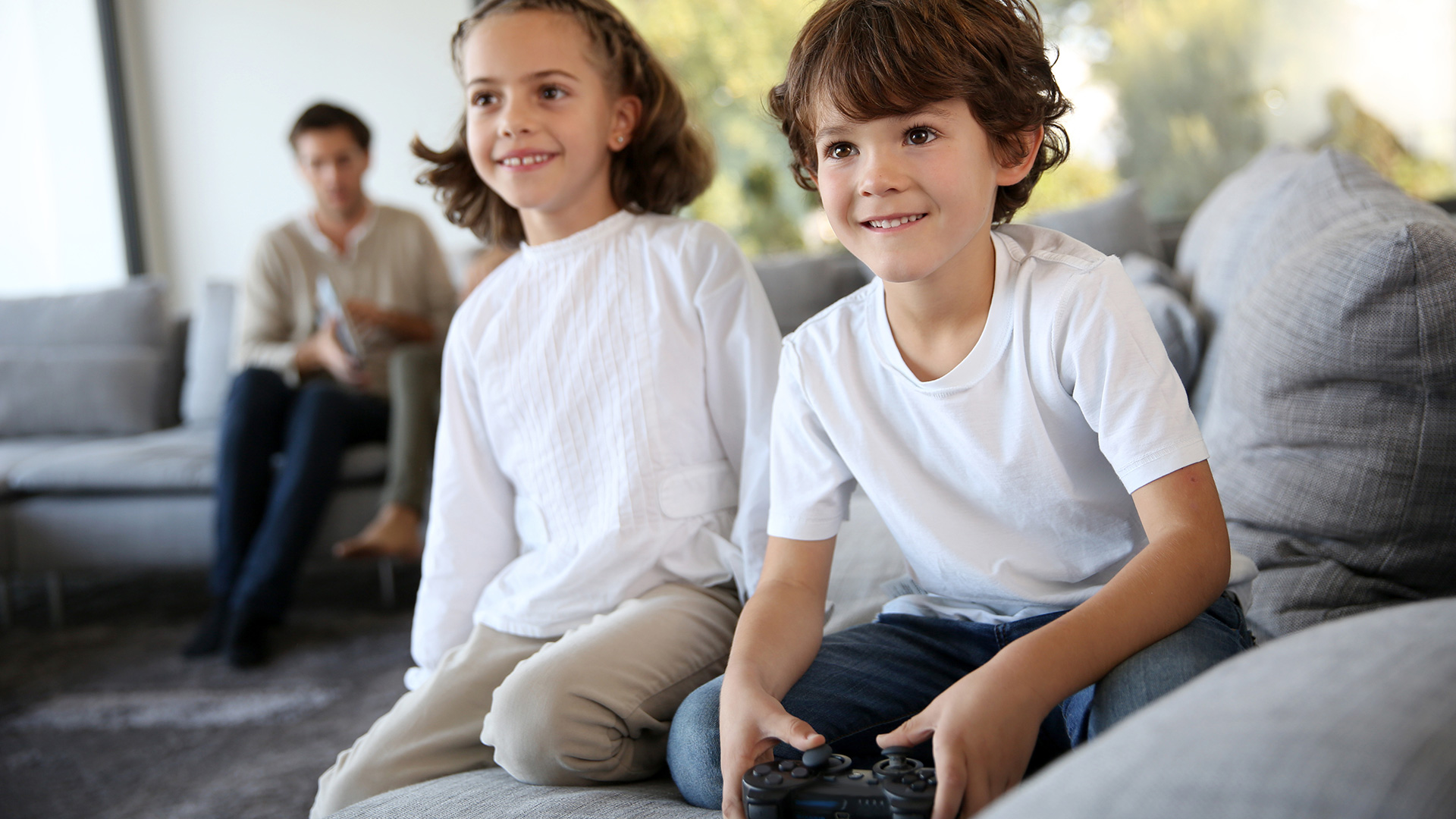 Two kids sitting on sofa with playing video games